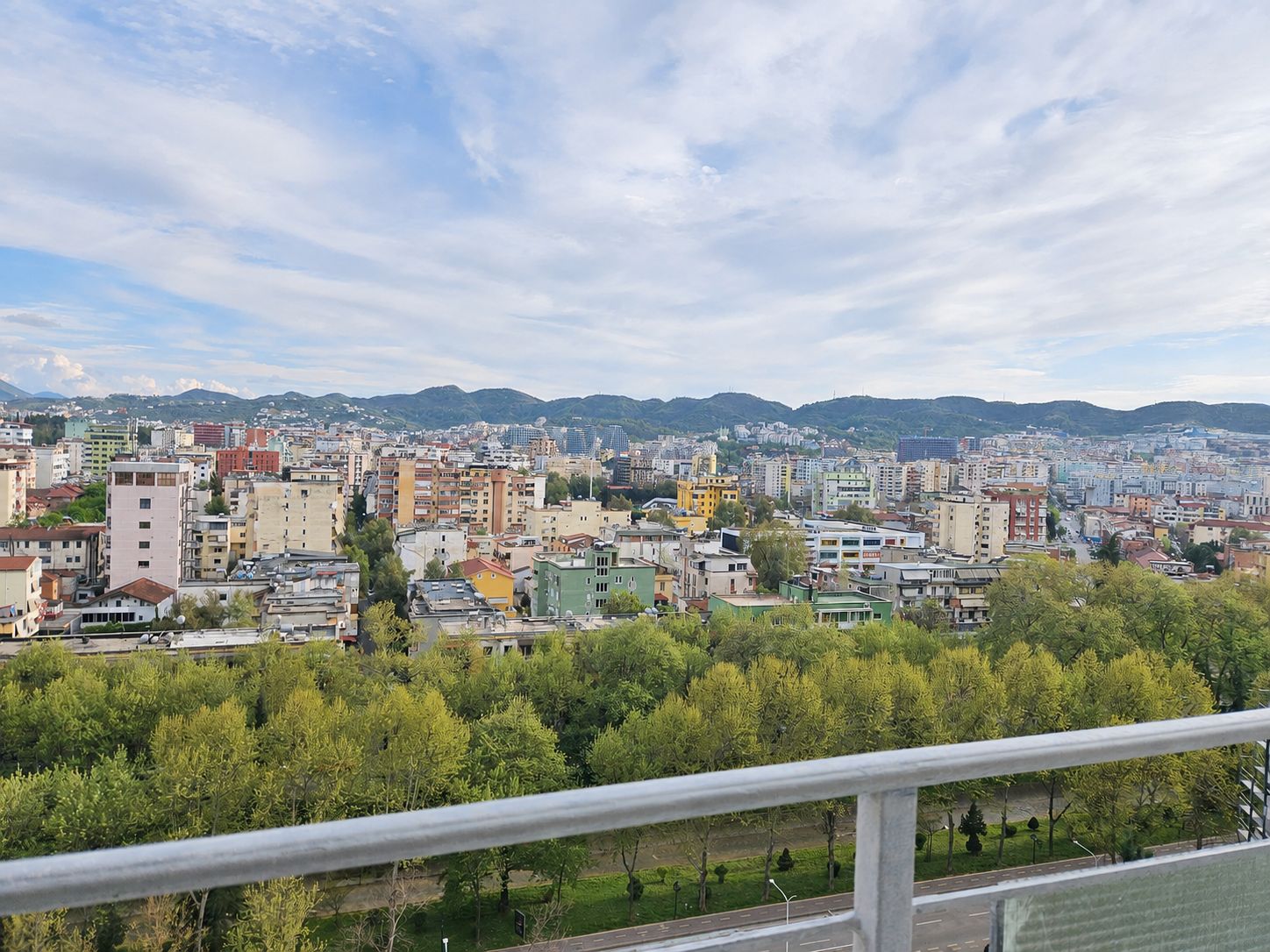 A cityscape with a variety of building types, including residential and commercial structures, and a backdrop of hills.