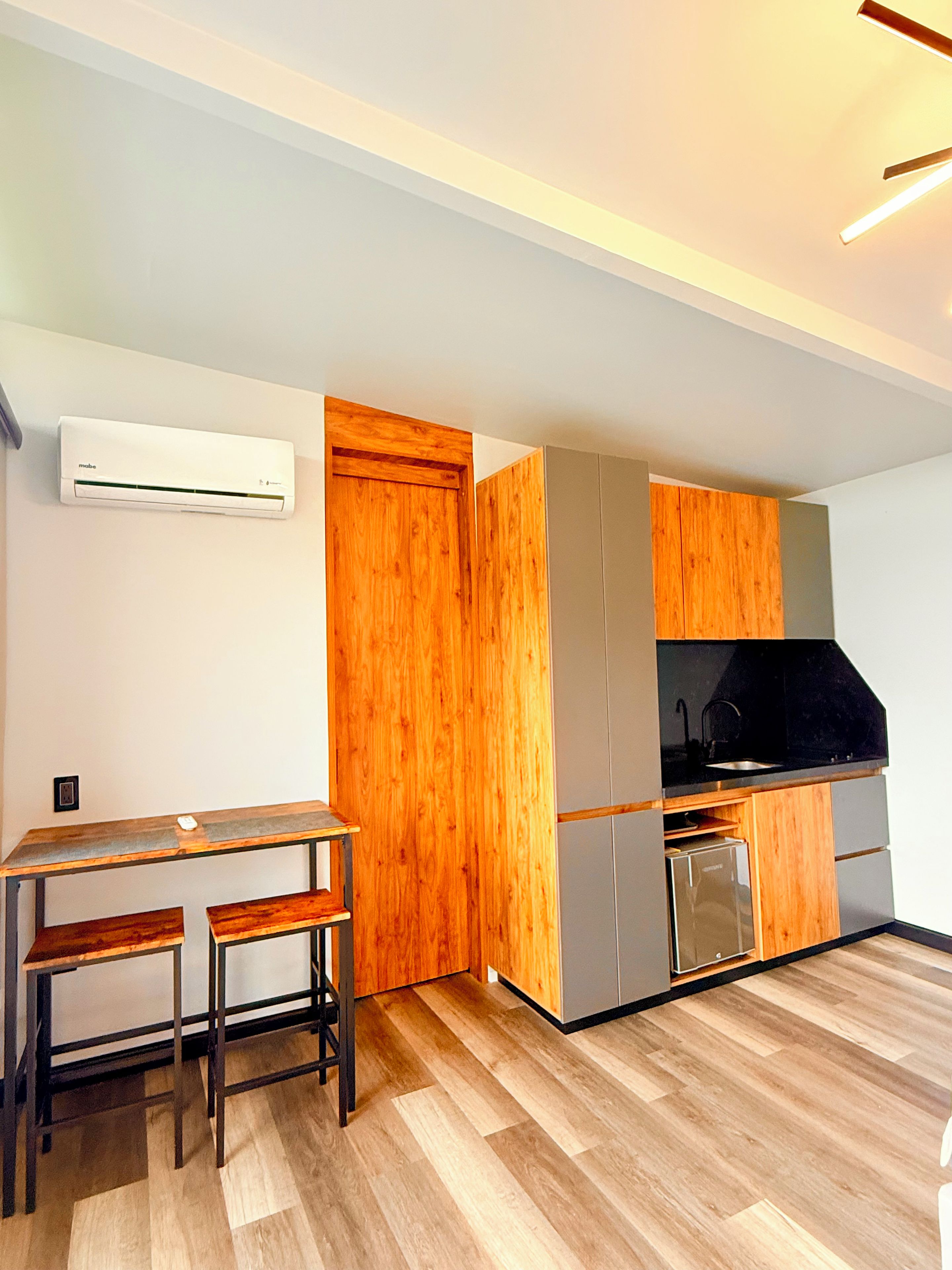 A modern kitchen with wooden cabinets, a built-in oven, and a black countertop.
