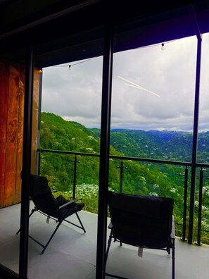 A balcony with two chairs overlooking a lush green landscape.