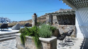 Una terraza con escalones de piedra, mobiliario exterior y vista al mar.