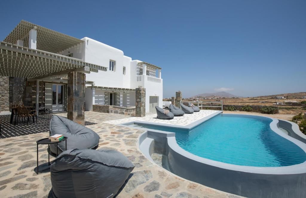 Un edificio moderno con piscina, mobiliario exterior y vistas del paisaje.