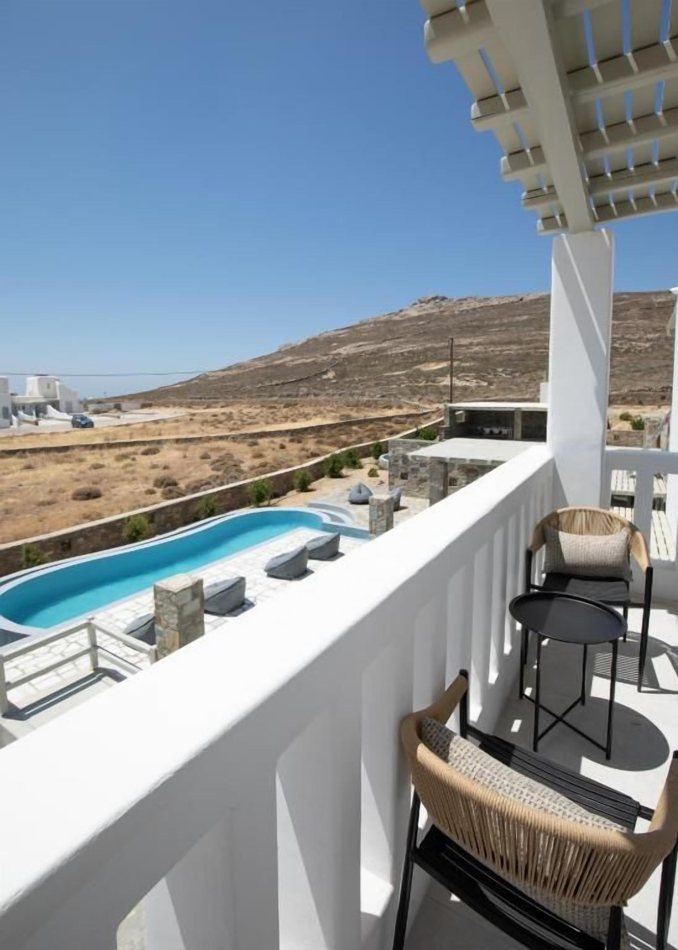 Un balcón con piscina, mobiliario exterior y vistas a un paisaje montañoso.