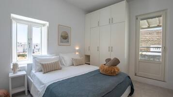 Un dormitorio con cama, mesita de noche, armario y ventana con vistas.