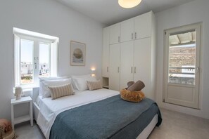 Un dormitorio con cama, mesita de noche, armario y ventana con vistas.
