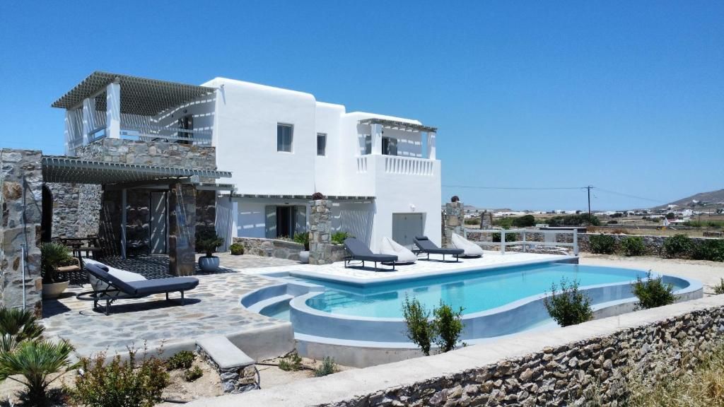 A modern villa with a swimming pool, outdoor seating, and a stone facade.