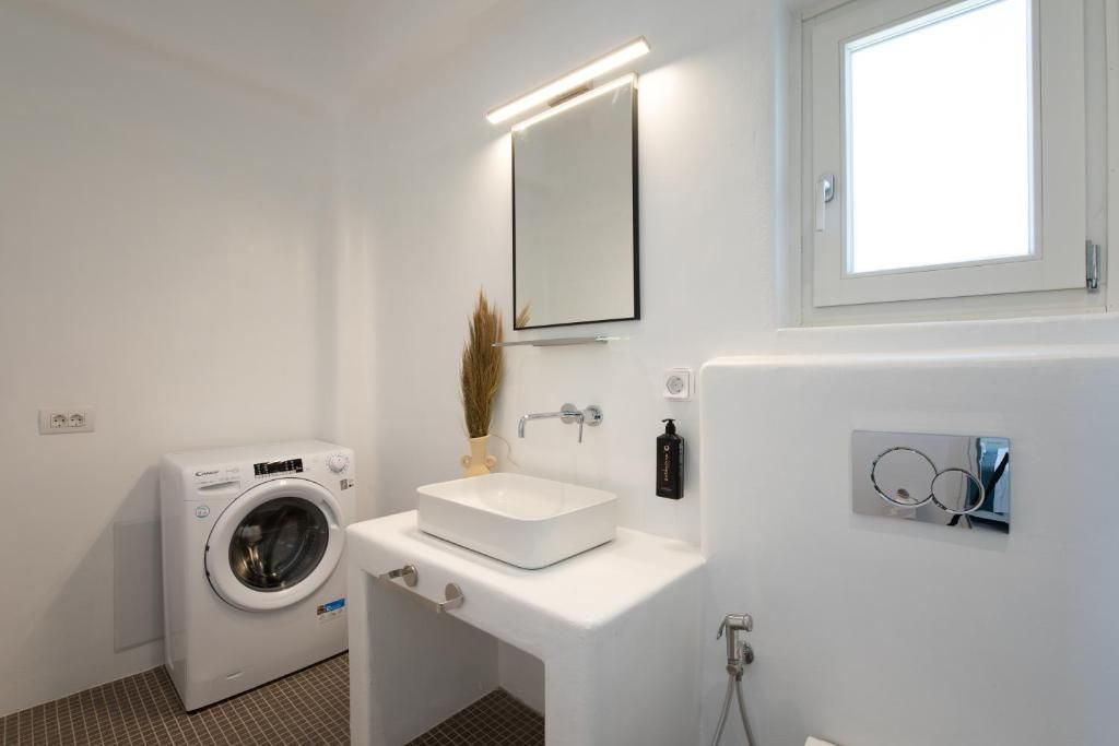 A modern bathroom with a built-in washing machine, a sink, and a mirror.