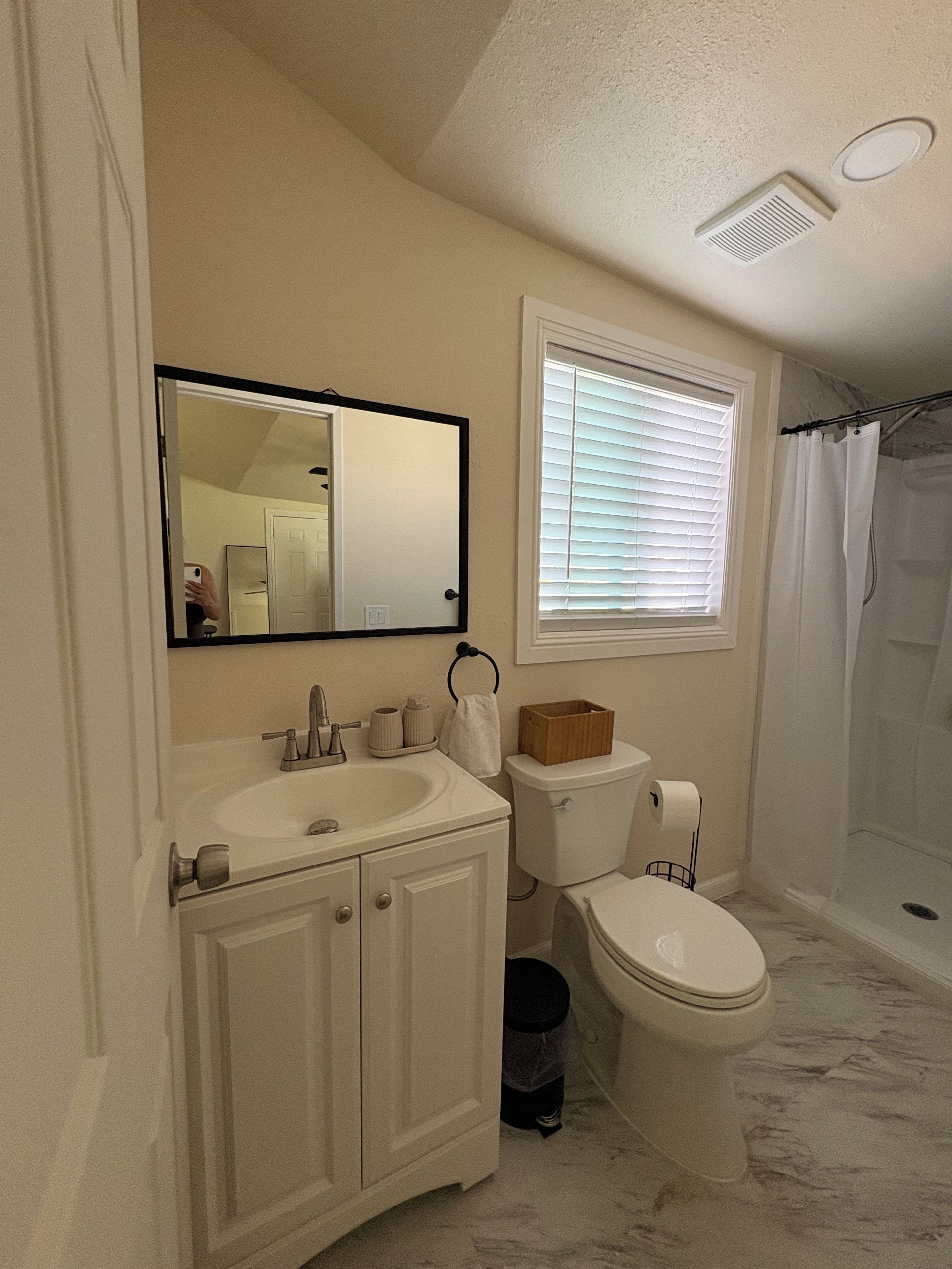 Une salle de bain équipée d’un lavabo, d’un miroir, de toilettes et d’un rideau de douche.