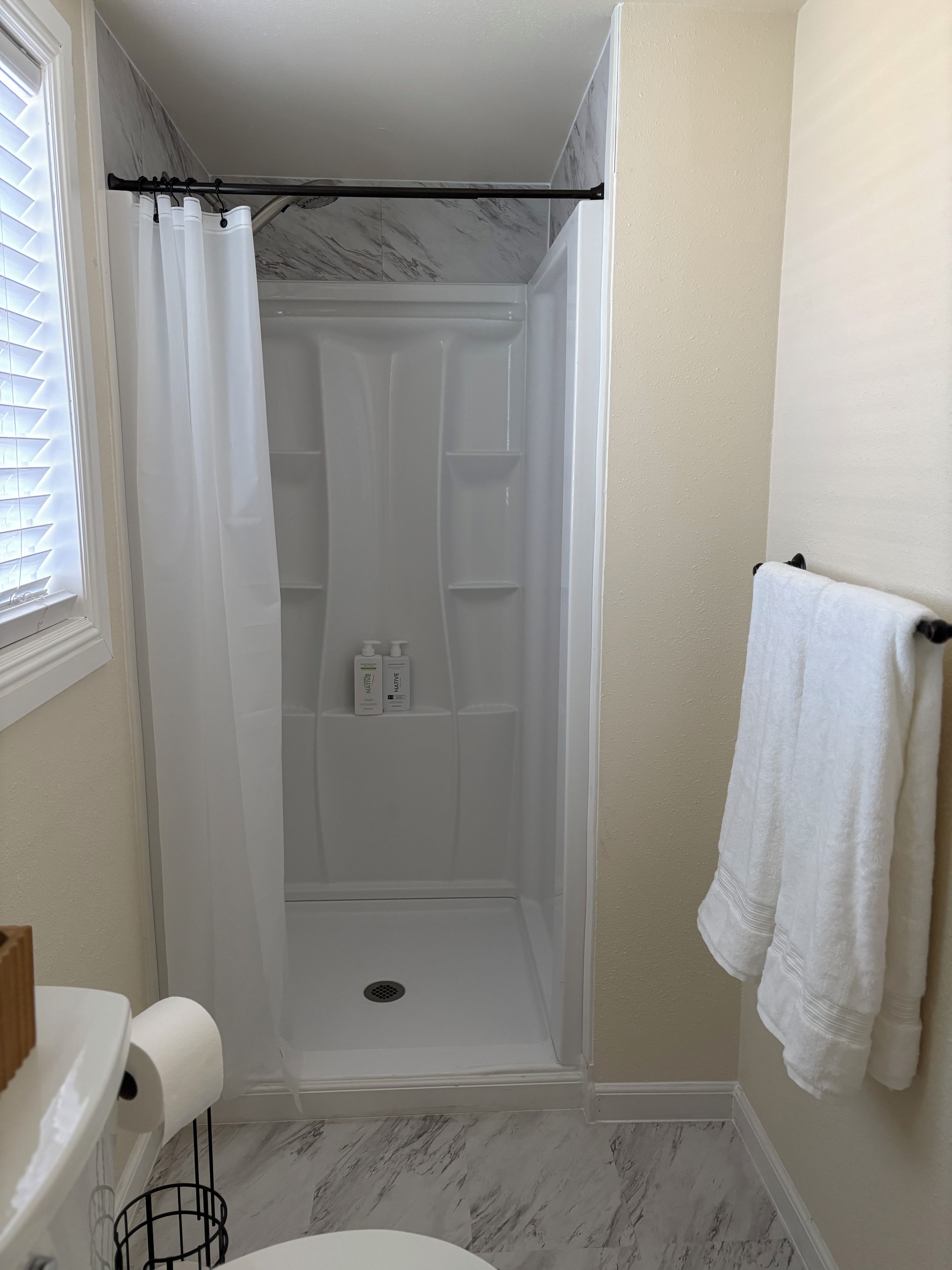 Une salle de bain avec douche, toilettes et porte-serviettes.