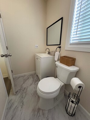 Une salle de bain avec des toilettes, un lavabo et un miroir.