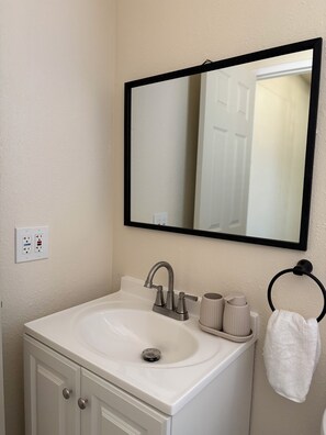 Une salle de bain avec un lavabo blanc, un miroir et un porte-serviette.