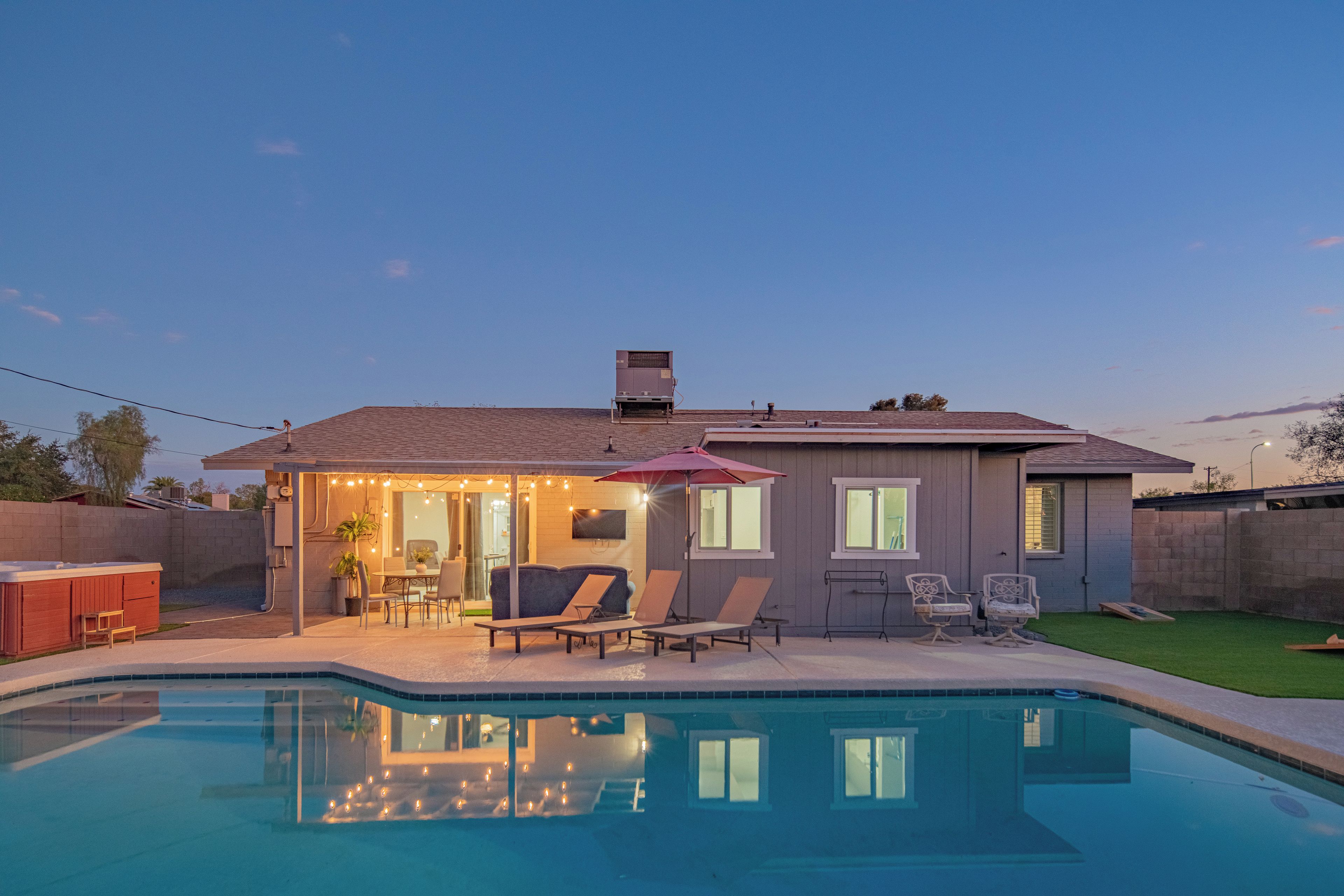 A residential property with a swimming pool, outdoor seating area, and a covered patio.