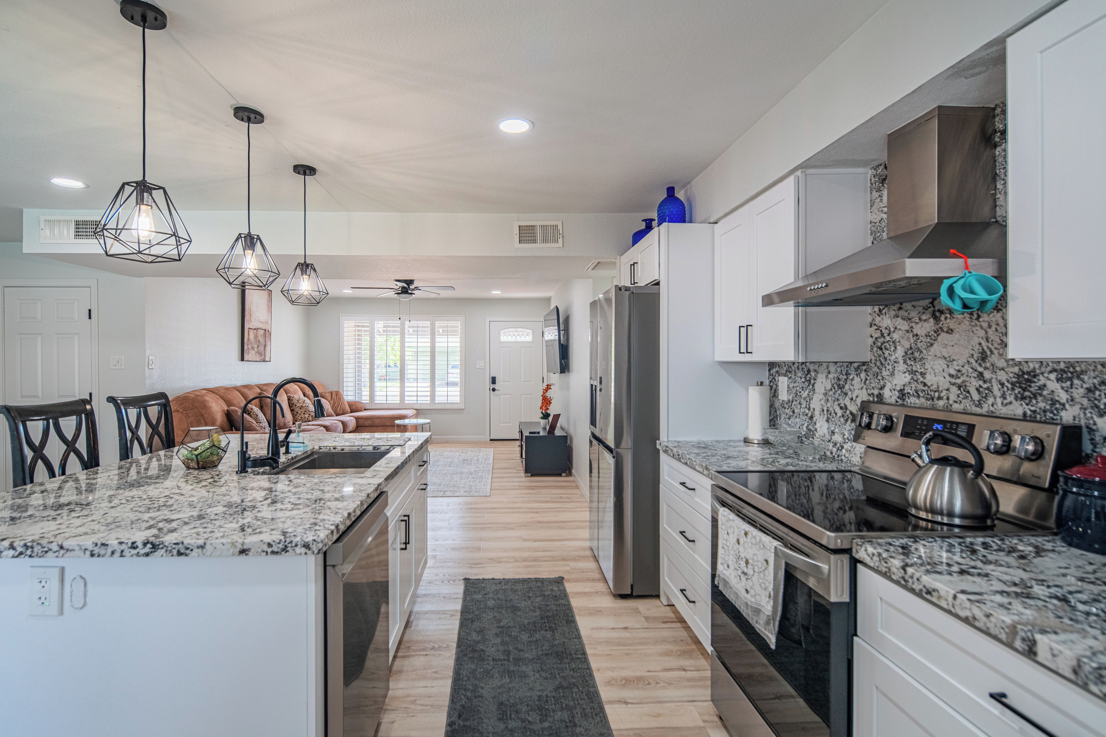 A modern kitchen with a central island, stainless steel appliances, and pendant lighting.