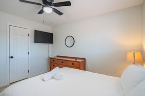 A hotel room with a bed, a dresser, a television, a ceiling fan, and a mirror. - Spacious 4BDR Tempe Getaway Hot Tub + Pool 5 Min to ASU (Tempe)