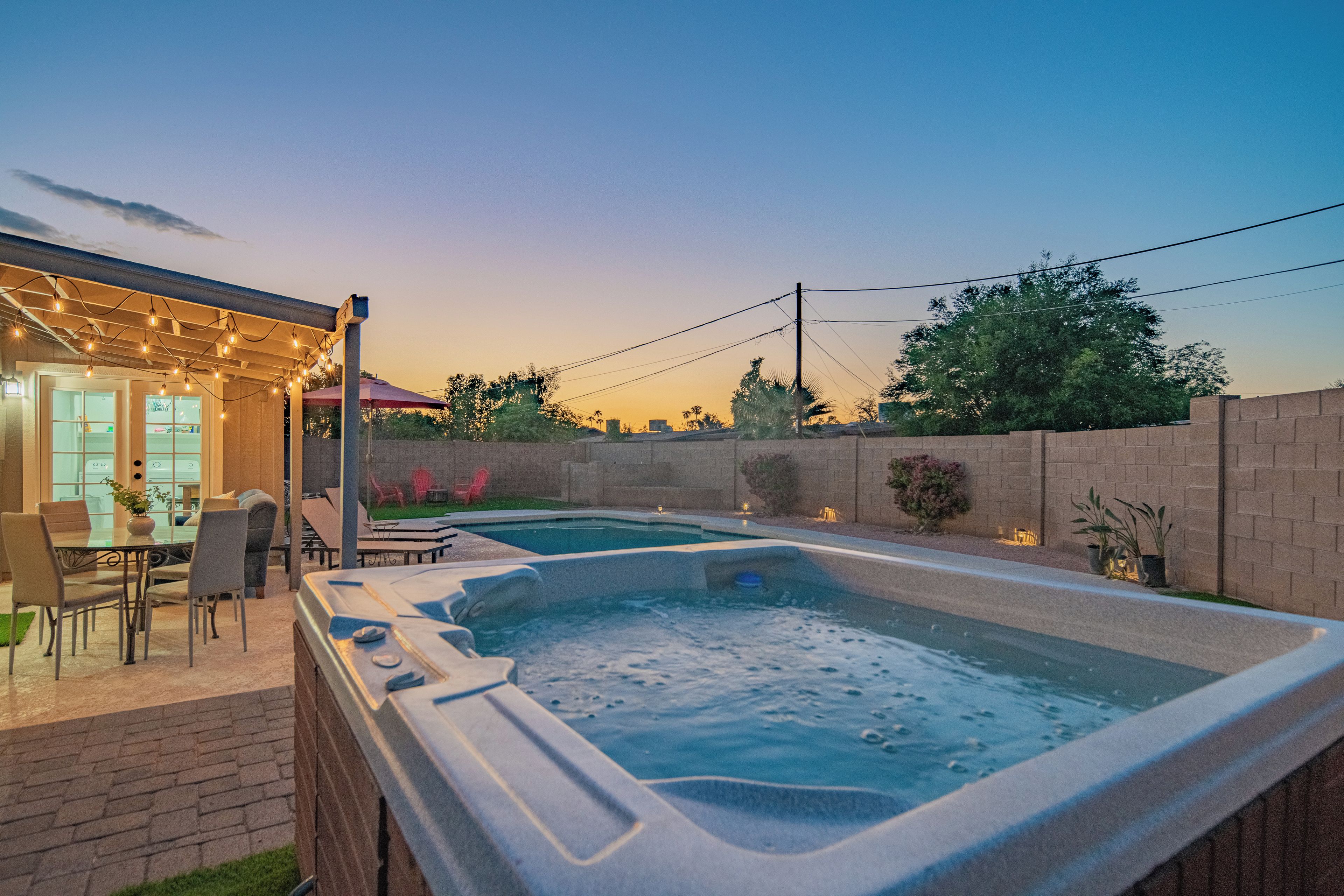 A backyard with a hot tub, outdoor seating, and a patio area.