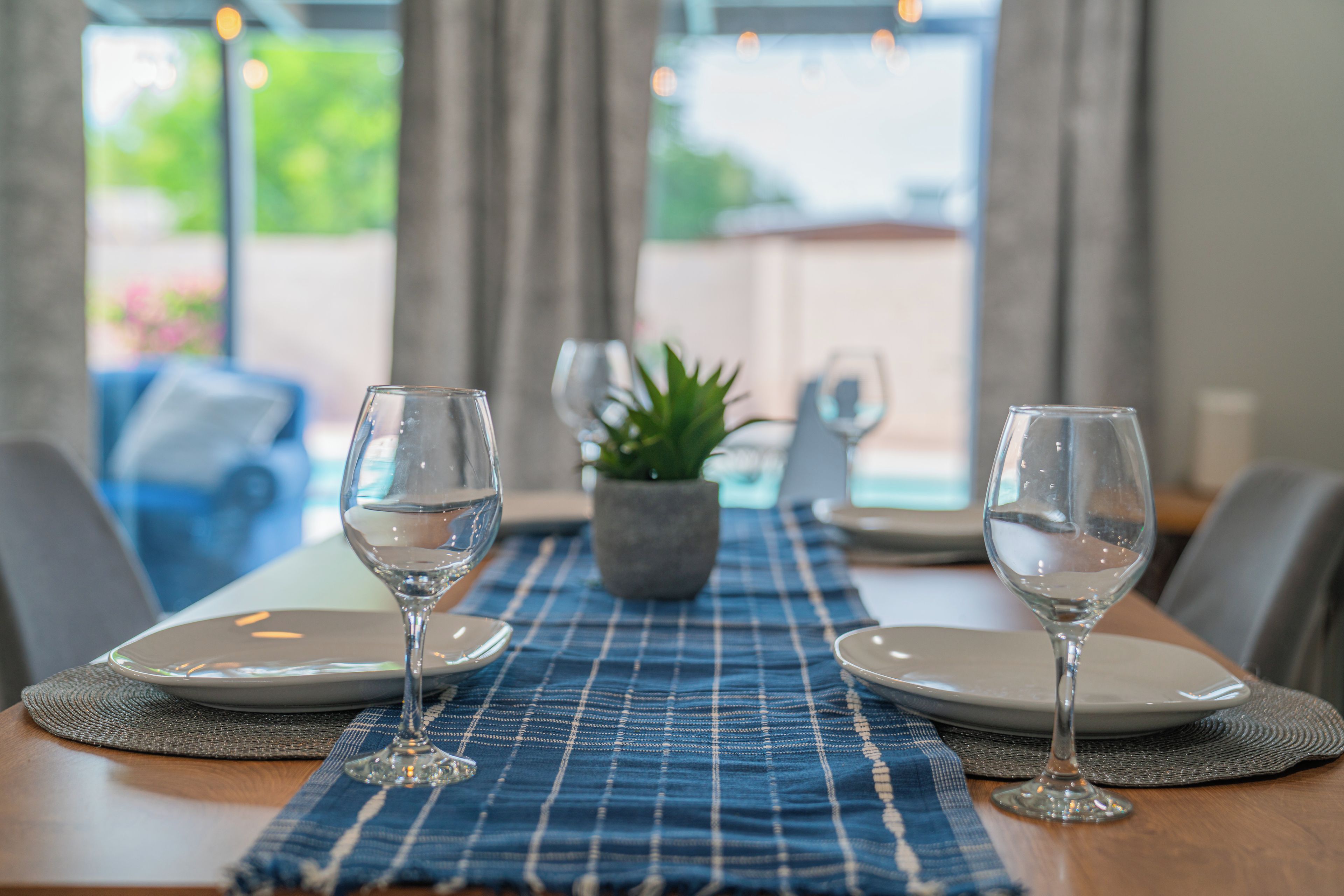 A dining table with two wine glasses, plates, and a placemat.