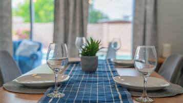 A dining table with two wine glasses, plates, and a placemat.