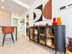 Ein modernes Interieur mit einem schwarzen Schrank, einem braunen Sessel und einem großen abstrakten Kunstwerk an der Wand.