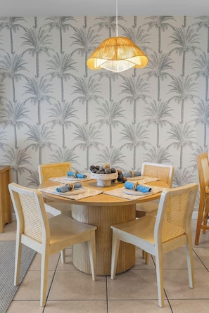A dining area with a round table, white chairs, and a hanging light fixture. - Heated Pool| Steps 2 Beach| King + Bunks| Kid Gear (Destin)