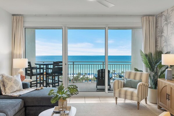 A spacious living room with a large sliding glass door leading to a balcony with a view of the ocean. - Heated Pool| Steps 2 Beach| King + Bunks| Kid Gear (Destin)