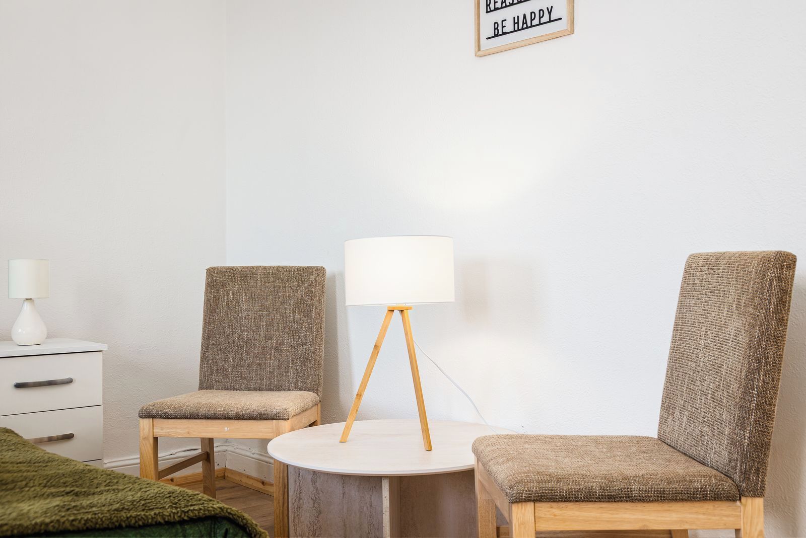 A room with two chairs, a small table, a lamp, and a sign on the wall.