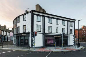 Ein Eckgebäude mit einem Schild mit der Aufschrift 'Harrogate Corner' und einem gut erkennbaren Eingang.