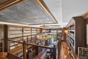 Eine Bibliothek mit Bücherregalen, einer Chandelier und einer Treppe.