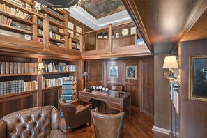 A library with bookshelves, a desk, leather chairs, and a clock on the wall. - Villa Imma in Castellammare di Stabia (Castellammare di Stabia)