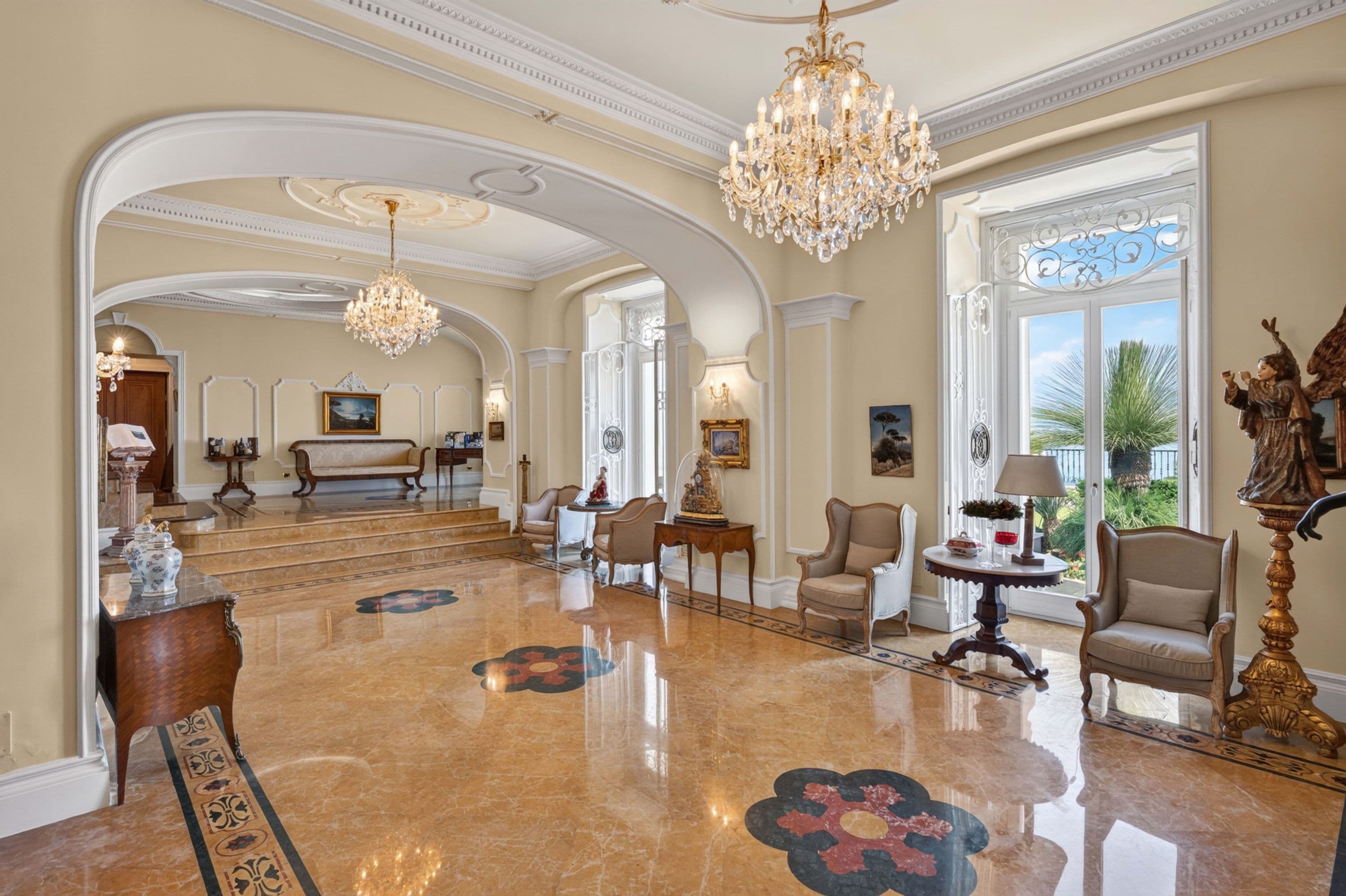 Un vestíbulo amplio con suelo de mármol, candelabros elegantes y arquitectura clásica.