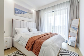 Een slaapkamer met een bed, nachtkastjes, een spiegel en een schilderij aan de muur.