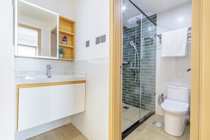 Een moderne badkamer met een glazen douchecabine, een wit wastafelmeubel en een toilet.