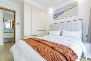 Ein modernes Schlafzimmer mit einem großen Bett, einem Nachttisch, einem Kleiderschrank und einem Bild an der Wand.