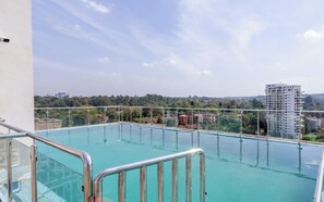 Ein Pool auf dem Dach mit freiem Blick auf umliegende Gebäude und Grünflächen.