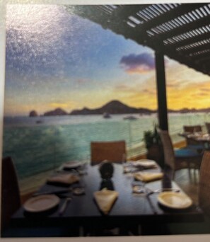 A dining area with a table set for two, overlooking a body of water with boats. - Villa del Palmar Cabo (San José del Cabo)