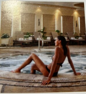 A person sitting on a patterned mat by a pool area with lounge chairs and tables in the background. - Villa del Palmar Cabo (San José del Cabo)