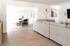 A modern living room with a sofa, a dining area with a table and chairs, and a lamp. - Modern Family Home & Guest House - Sleeps 9 (Ojai)