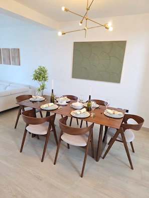 A dining area with a wooden table set for six, surrounded by six wooden chairs with cushioned seats. - Luxury Penthouse | 2BR | 2 Terraces | Estrrlla Garden Condos (Dominicus)