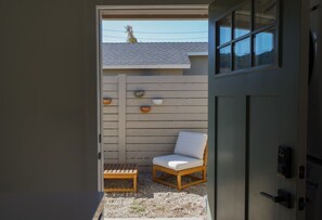 A wooden chair and a small table in a room with a grey door and a window.