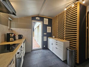 A modern kitchen with a built-in stove, a coffee maker, and a sink. There is a wooden slatted wall and a door leading to a hallway. - "The Barn" - Charming stay in the Loire valley close to castles and Beauval zoo (Saint-Aignan)