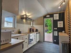 Une cuisine moderne avec des meubles blancs, un four encastré et une machine à café.
