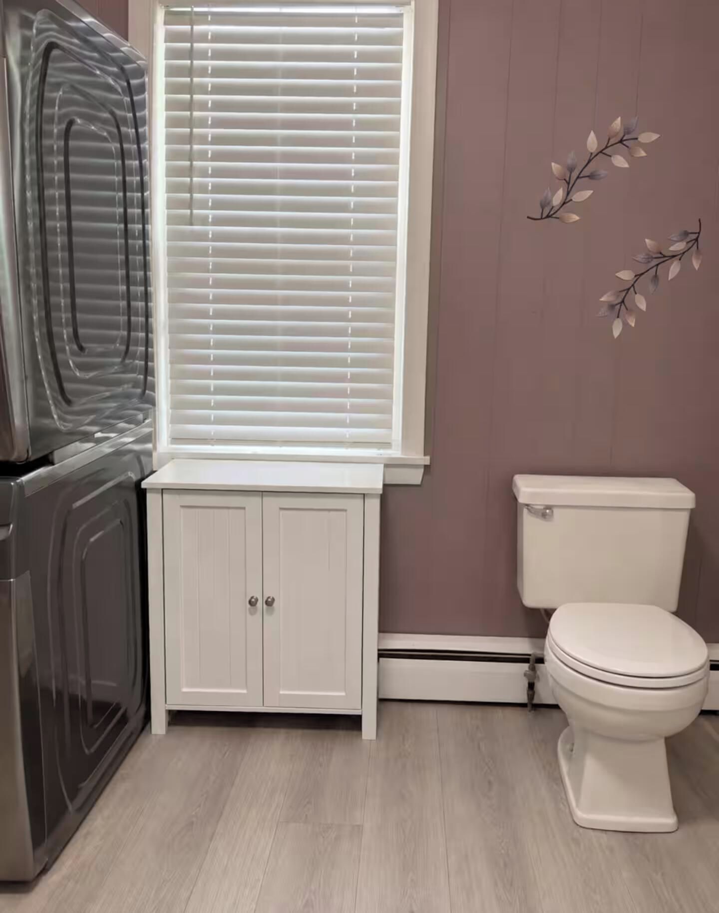 Un bagno con il water, un armadietto e una finestra con persiane.