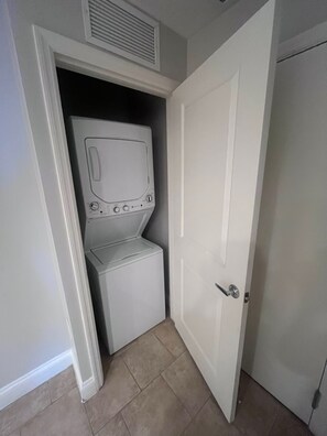 A laundry room with a washing machine and dryer, a door, and a vent above the dryer. - Sheraton Vistana Villages Spacious 1 BR Premium Villa Orlando Fl. (Orlando)