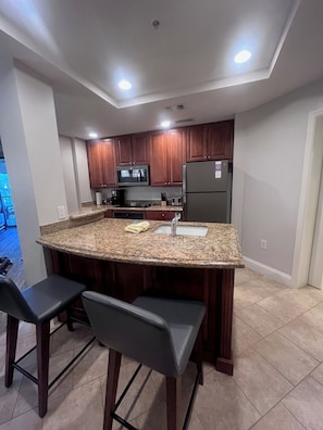 A kitchen with granite countertops, wooden cabinets, a stainless steel refrigerator, and a built-in microwave. - Sheraton Vistana Villages Spacious 1 BR Premium Villa Orlando Fl. (Orlando)