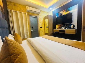 Ein Hotelzimmer mit einem Bett, einem Fernseher, einem Schreibtisch mit Wasserkocher und einer Dusche.