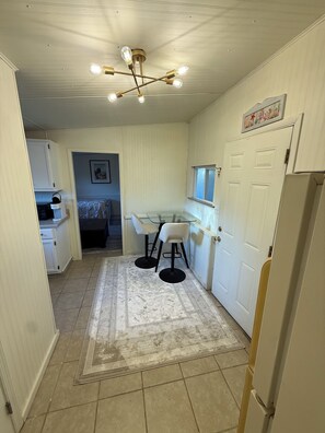 A compact kitchen with a dining area, a refrigerator, and a ceiling light fixture.