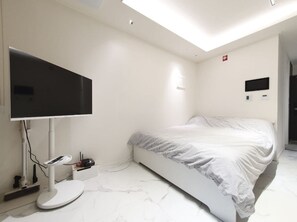 Ein modernes Schlafzimmer mit einem Bett, einem flachbildfernseher an der Wand und einer Deckenleuchte.