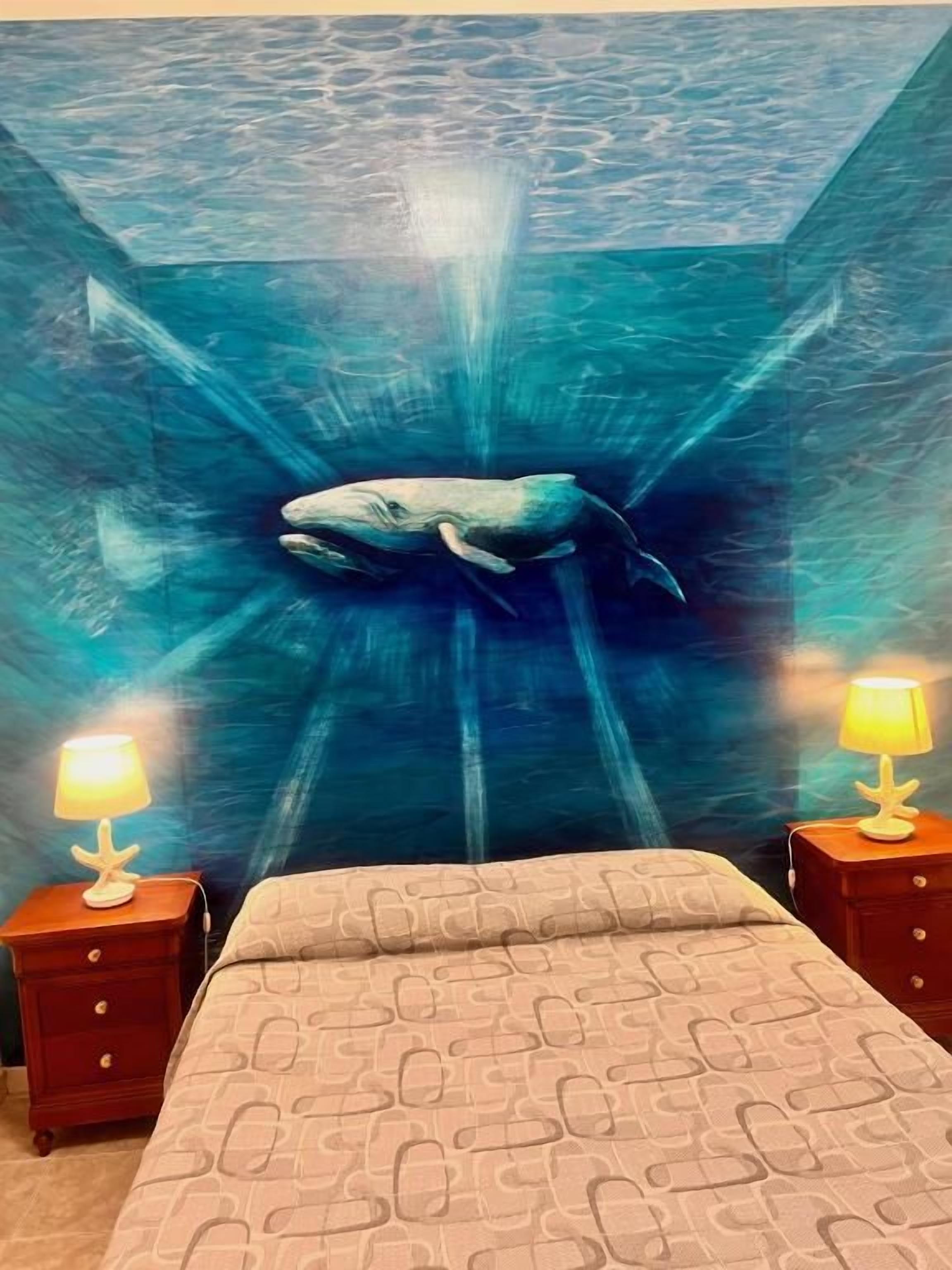 Ein Schlafzimmer mit einem Bett, zwei Nachttischen und einem Wandbild eines Wals.