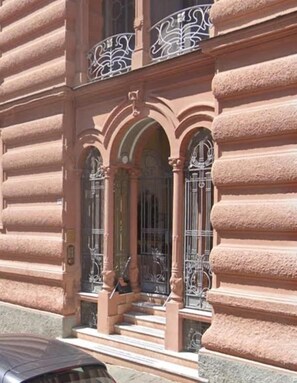 A building with a grand entrance featuring ornate ironwork and a staircase leading to a door with a glass panel. - CORALLI DI MARE 5 TERRE-JRE (La Spezia)