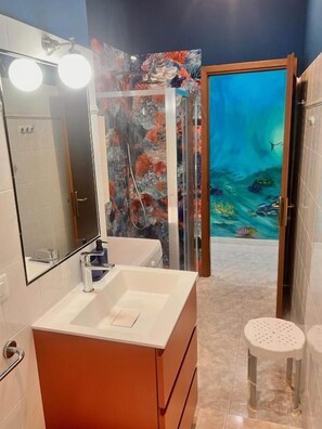 A bathroom with a white sink, a mirror, and a shower with a glass door. - CORALLI DI MARE 5 TERRE-JRE (La Spezia)
