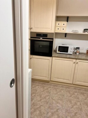 A kitchen with beige cabinets, a microwave, and an oven. - CORALLI DI MARE 5 TERRE-JRE (La Spezia)
