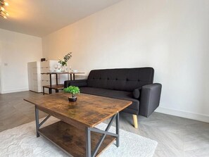 A modern living room with a dark sofa, a wooden coffee table, and a small plant. - AO Arena • Parking • Victoria Station (Manchester)